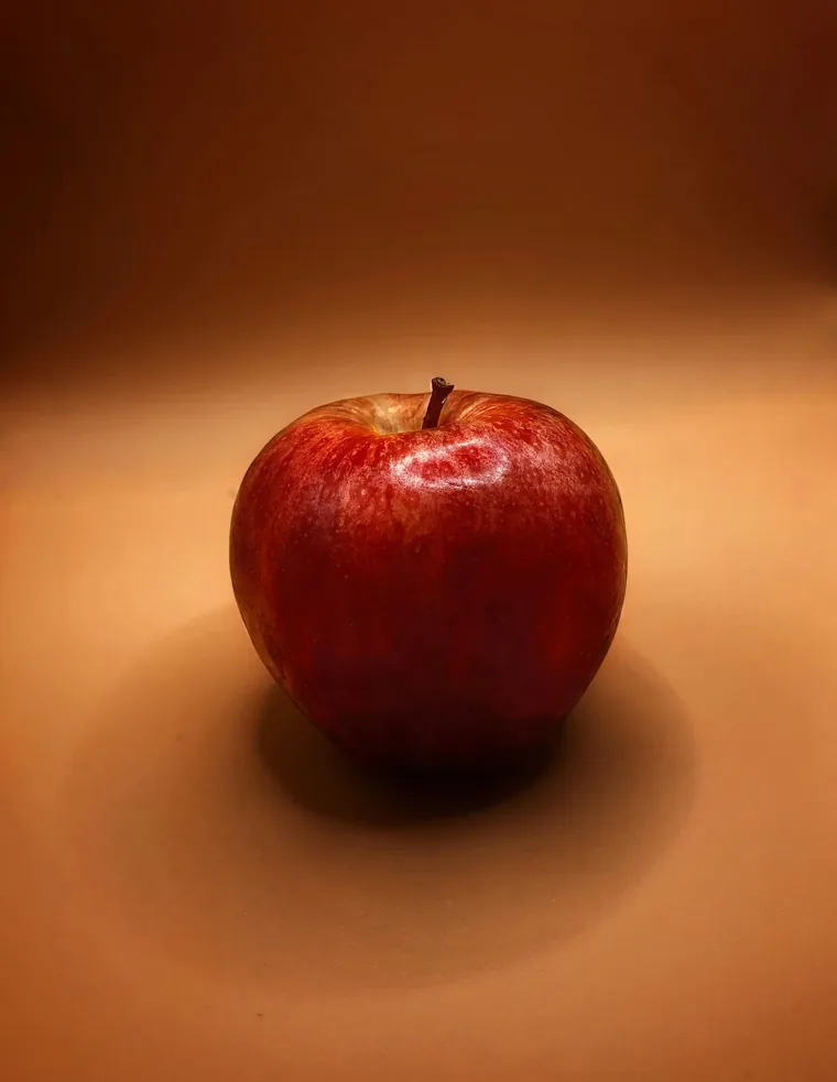 A single red apple photographed against a warm background