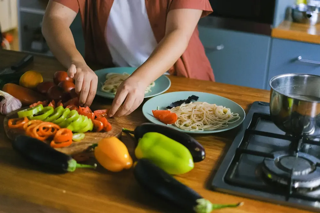 Someone preparing vegetables and pasta in a home kitchen